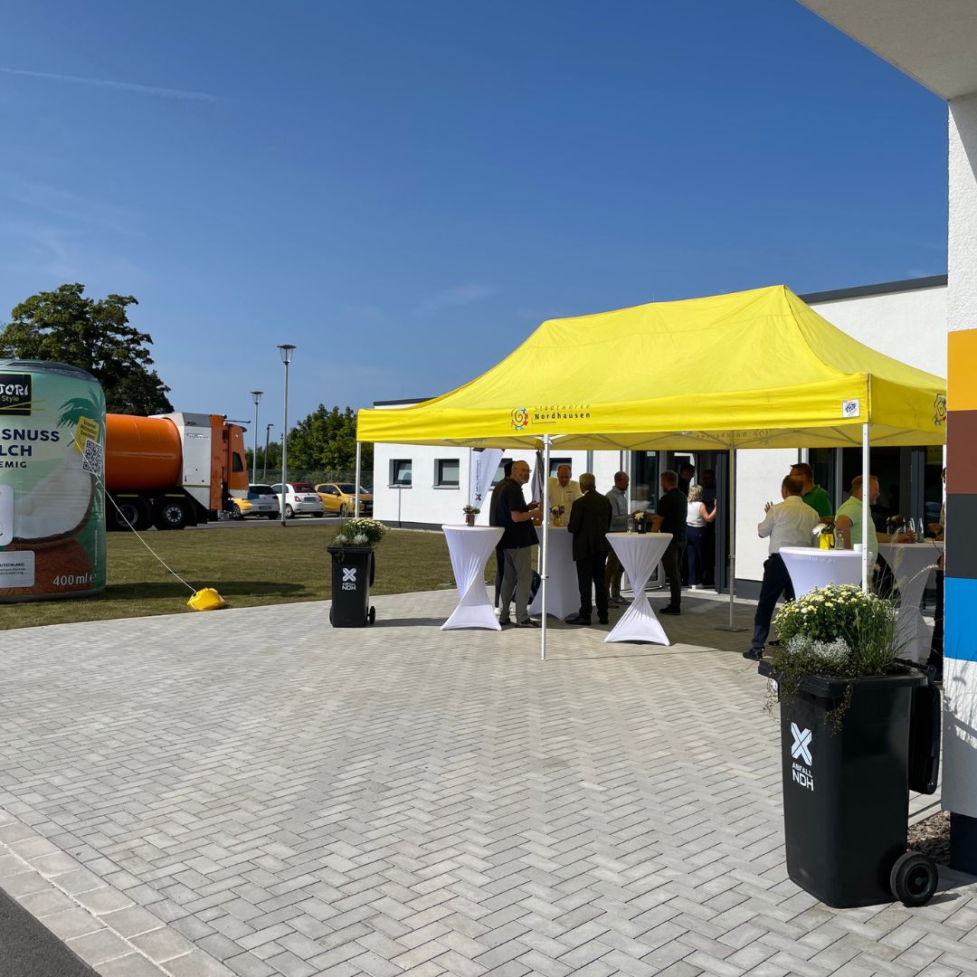 Gelber Pavillon steht vor dem Gebäude und Menschen stehen darunter